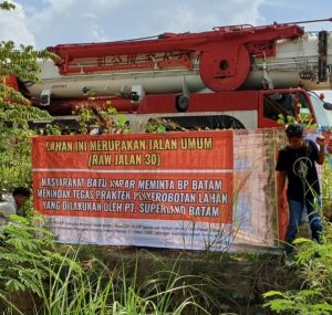 Warga Tanjungsengkuang Pasang spanduk protes didepan kawasan pergudangan milik PT Superland Batam. Mereka mendesak agar BP Batam segera membuka jalan ROW 30 yang selama ini digunakan tempat parkir alat berat milik tenant dibawakan pergudangan tersebut. Foto : ubay