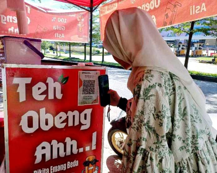 Sala satu pembeli tengah melakukan pembayaran menggunakan QRIS untuk melakukan pembayaran di gerai Teh Obeng Ahh...!. Foto : Tengku Bayu