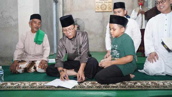 Kepala BP Batam, Amsakar Achmad, memberikan tandatangan ke anak-anak setelah menggelar sholat taraweh. Foto : ist
